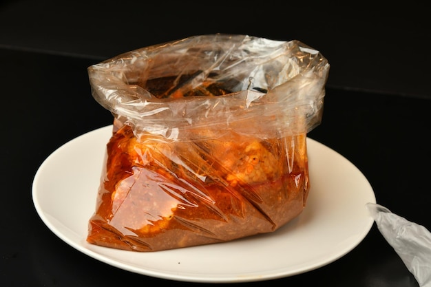 Een zak vlees ligt op een bord met een zwarte achtergrond.
