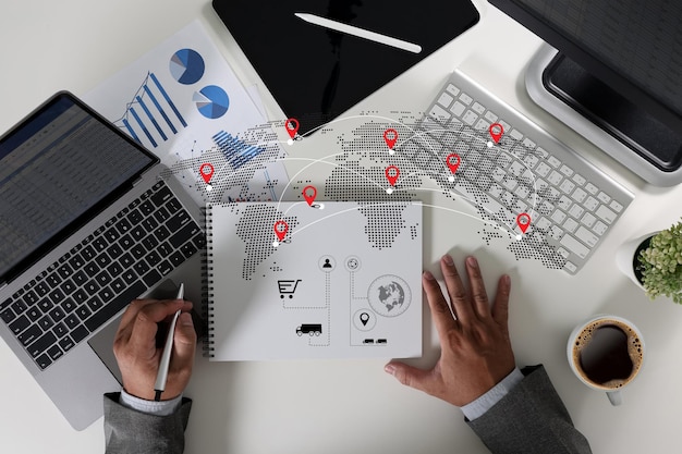 Een zakenman die op een laptop en computer werkt in een kantooromgeving met verschillende kantoorbenodigdheden rond iot Smart logistics