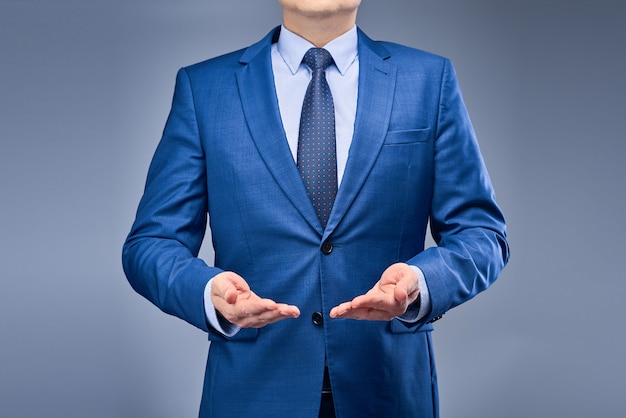 Een zakenman in een blauw pak houdt zijn handen voor hem