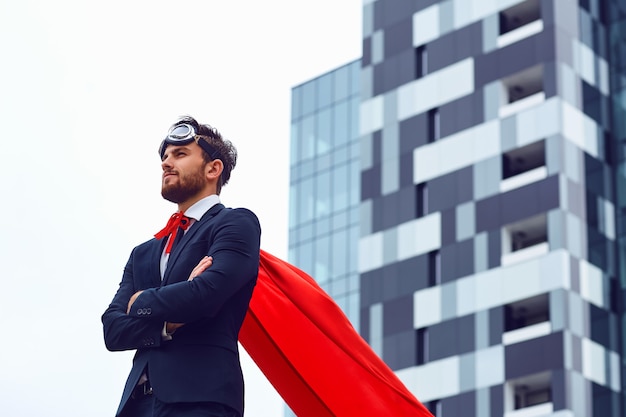 Een zakenman in een superheldenkostuum staat tegen de achtergrond van een zakelijk gebouw.
