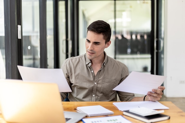 Een zakenman met een verkoopdocument dat de verkoopafdeling samenvat, hij kijkt ontevreden als hij rapporten ziet van dalende verkopen, hij vertoont tekenen van stress. mislukt verkoopbeheerconcept.