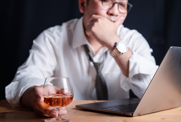 Een zakenman met een whiskyglas Vanwege de stress van 's nachts hard werken
