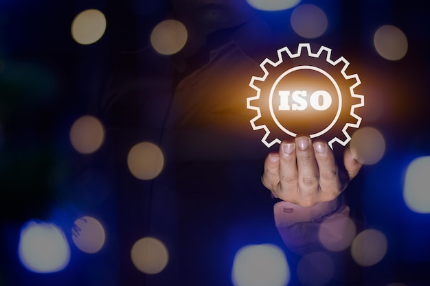 Een zakenman met het ISO-certificaatpictogram ISO-verwerkingsstap bokeh licht standaardkwaliteit documentcontrole voor organisatie- en industriebeheerproducten kopieer ruimte voor ontwerp of tekst