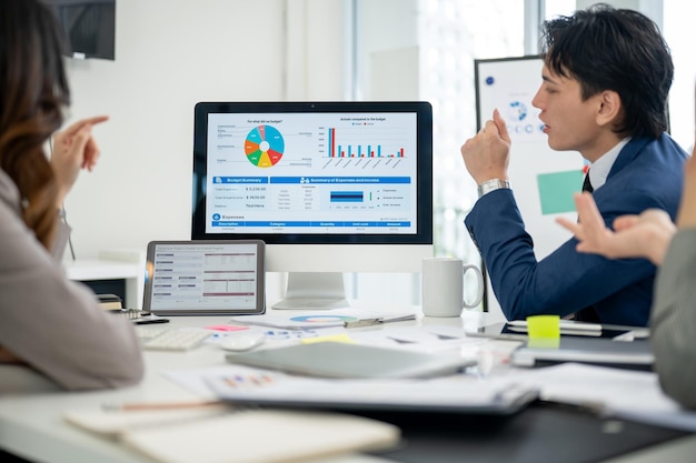 Een zakenman of een mannelijke kantoormedewerker die met zijn collega's over het financiële verslag op de monitor praat