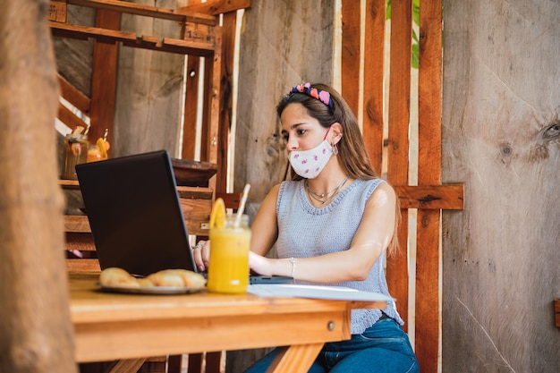 Een zakenvrouw die op haar laptop werkt terwijl ze vruchtensap drinkt in een bar.