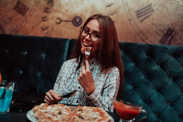 Foto een zakenvrouw die tijdens een lunchpauze pizza eet in een modern restaurant. selectieve focus. foto van hoge kwaliteit