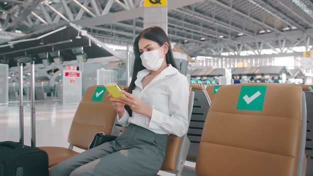 Een zakenvrouw draagt een beschermend masker op de internationale luchthaven, die reist onder de Covid-19 pandemie