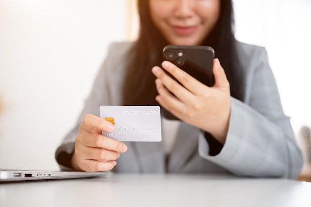 Een zakenvrouw houdt een smartphone en een creditcard vast met behulp van online betalingen