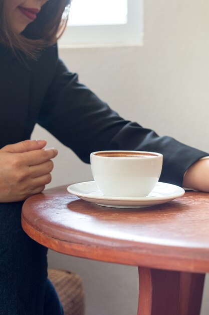 Een zakenvrouw houdt een witte koffiekopje tijdens het werk op de kantoortafel