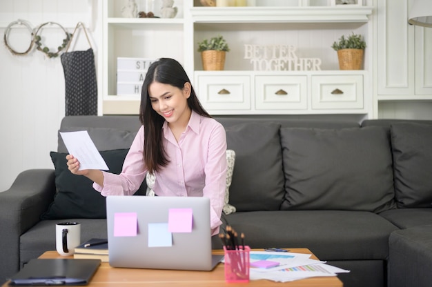 Een zakenvrouw werkt met laptop en analyseert de gegevens van de grafiek van de bedrijfsgroei in de woonkamer, werken vanuit huis, technologie bedrijfsconcept.