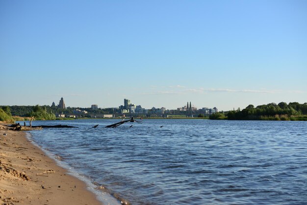 Een zandstrand met op de achtergrond een stad en een brug