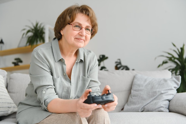 Een zeer emotionele oudere dame zit thuis op de bank en speelt videogames oma wint terwijl ze alleen thuis zit