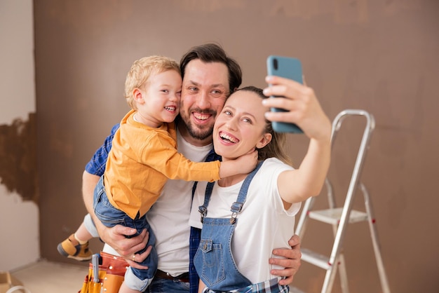 Een zeer glimlachende familie, een man van middelbare leeftijd, een blonde vrouw en hun schattige zoon nemen een selfie
