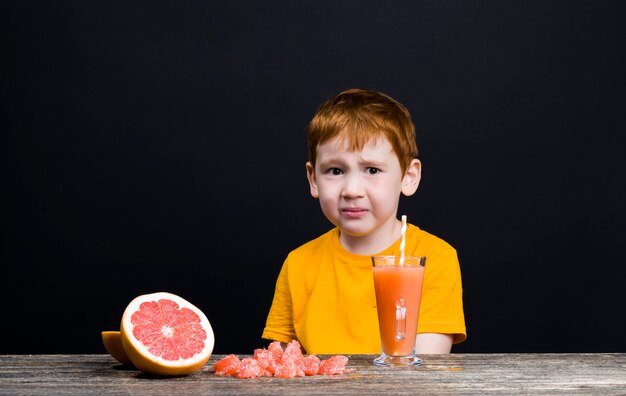 Een zeer mooie roodharige jongen met citrusvruchten grapefruit