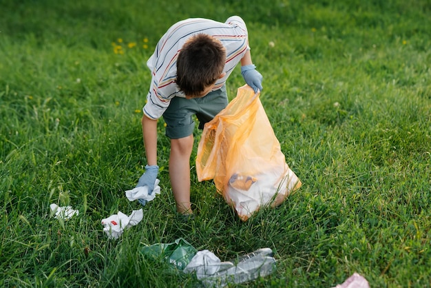 Een zevenjarige jongen bij zonsondergang houdt zich bezig met afvalinzameling in het park Milieuzorg recycling