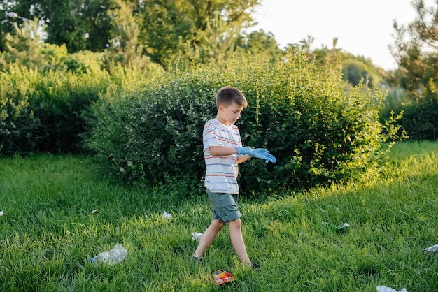 Een zevenjarige jongen is bij zonsondergang bezig met het ophalen van afval in het park. Milieuzorg, recycling.