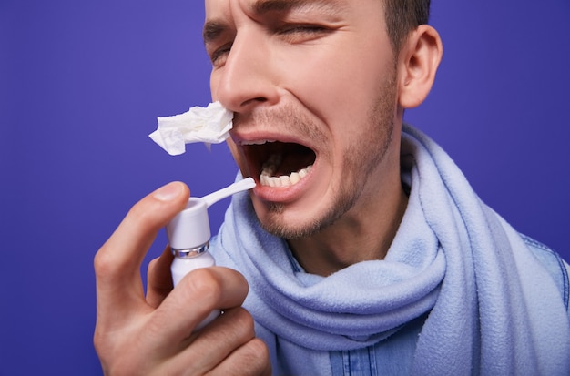 Een zieke man in denim shirt met inhalator en servet in zijn neus