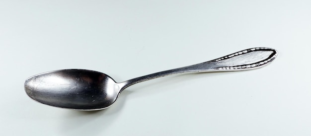een zilveren lepel met een zwarte handvat op een wit oppervlak