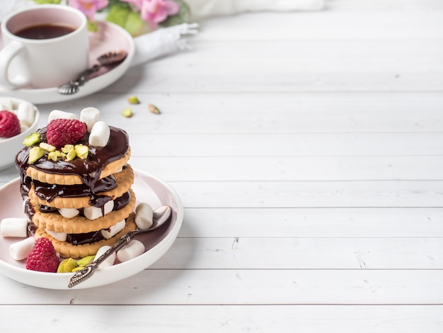 Een zoet dessert van een chocolade koekje framboos en marshmallow Kopje koffie op een lichte tafel
