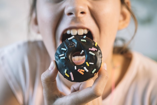 Een zoete donut in de hand klein meisje eet cupcake rommelig het meisje eet zoete gebak een open mond en een chocolade donut