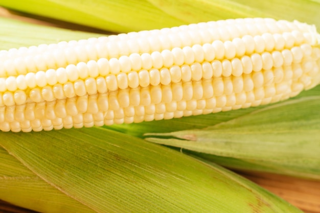 Een zoete gele rauwe melk maïskolven maïs met witte korrel groen vers ingrediënt product Liggen op houten achtergrond tafel Groene sappige lommerrijke strepen Kant koken voorbereiding schotel Close-up