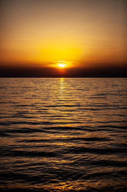 Een zonsondergang boven de zee met daarachter de ondergaande zon