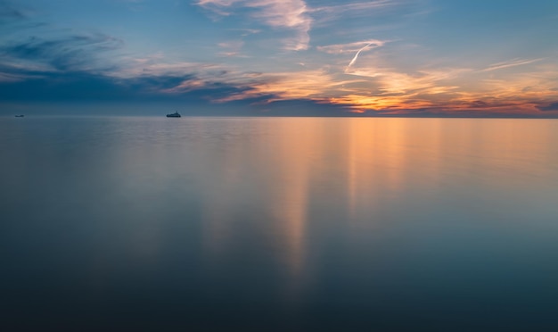 Een zonsondergang boven de zee met in de verte een boot