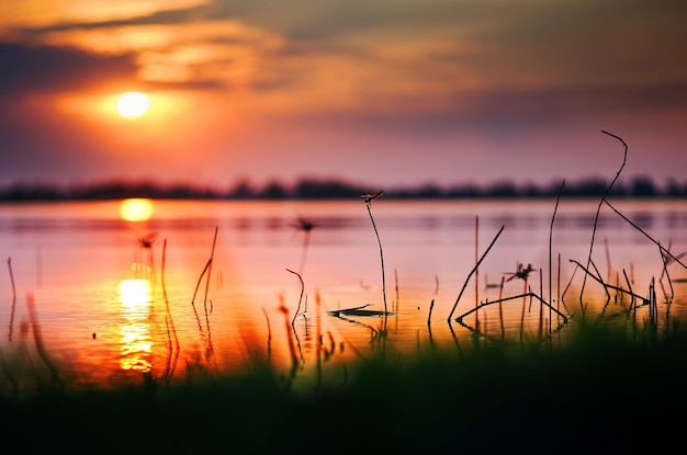 Een zonsondergang boven een meer met daarachter de ondergaande zon