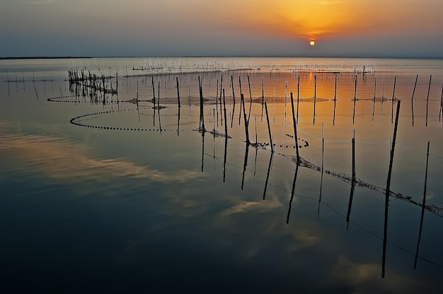 Een zonsondergang boven een meer met een net op de voorgrond