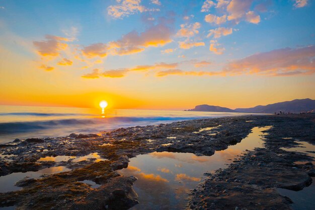 Een zonsondergang over de oceaan met een berg op de achtergrond