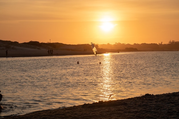 Foto een zonsondergang over het water met een zeilboot op de voorgrond