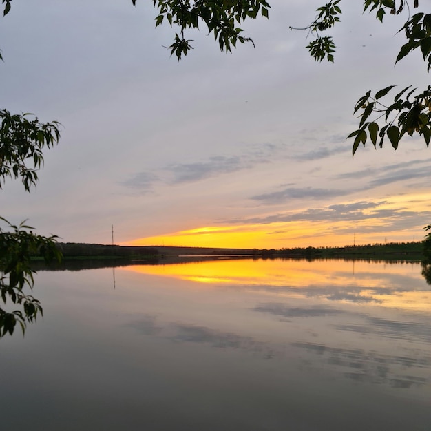 Een zonsondergang wordt weerspiegeld in het water en de lucht is oranje.