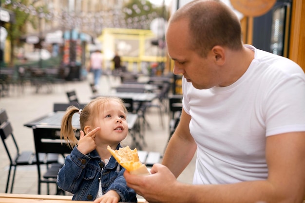 Een zorgzame papa voedt zijn schattige dochtertje