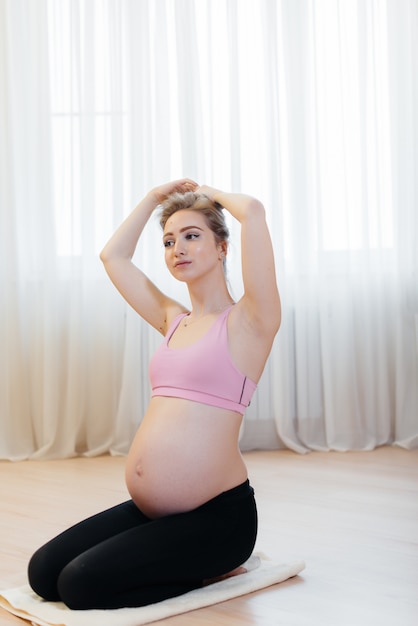 Een zwanger meisje doet thuis yoga. Gezondheid