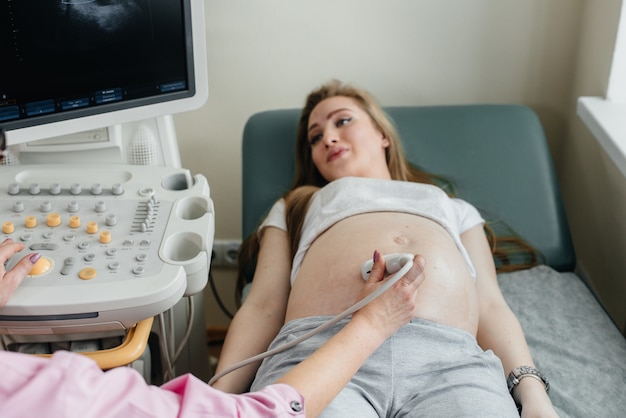 Een zwanger meisje heeft een echografie van de buik in de kliniek in close-up. Geneeskundig onderzoek