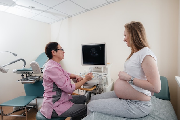 Een zwanger meisje wordt door een arts geadviseerd na een echo in de kliniek. Geneeskundig onderzoek