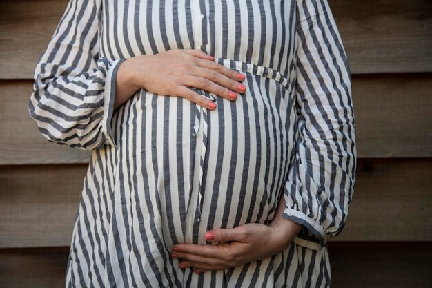 Een zwangere vrouw die haar babybuil vasthield, stond tegen een effen achtergrond