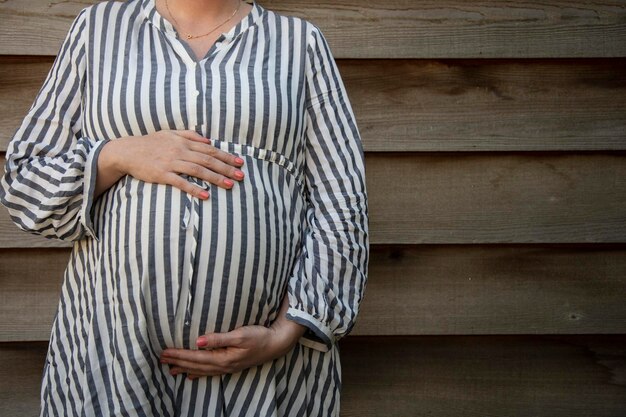 Een zwangere vrouw die haar babybuil vasthield, stond tegen een effen achtergrond