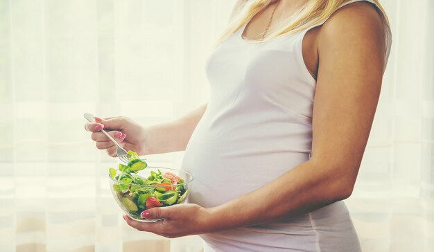 Een zwangere vrouw eet een salade met groenten