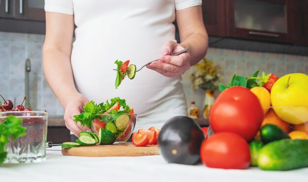 Een zwangere vrouw eet groenten en fruit