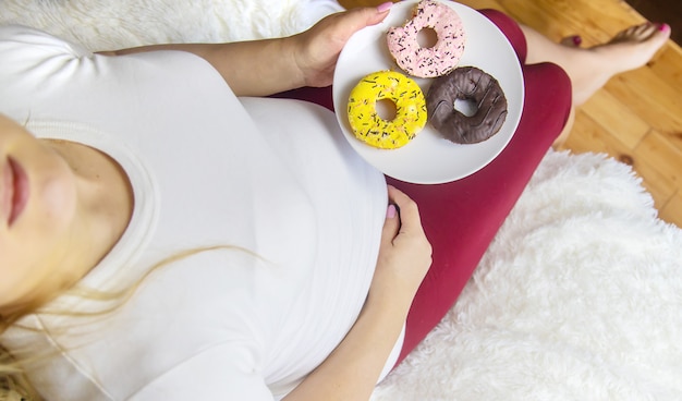 Een zwangere vrouw eet zoete donuts. Selectieve aandacht.