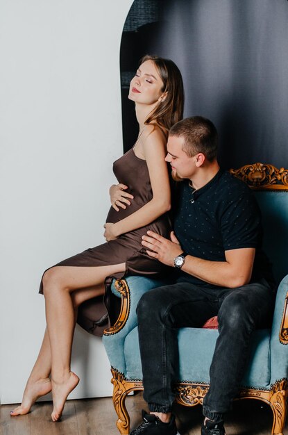 een zwangere vrouw en een man zitten in een stoel