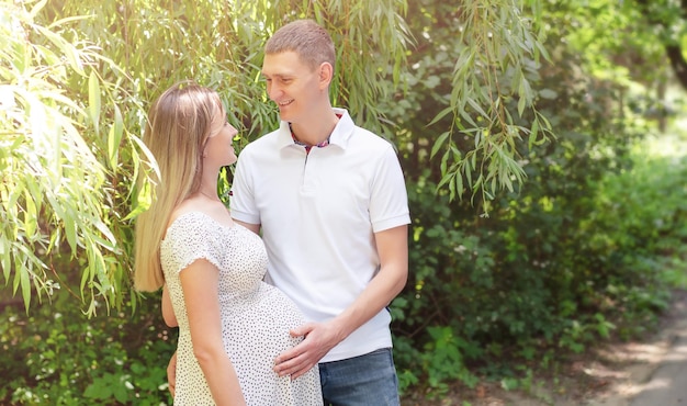 Foto een zwangere vrouw en haar man staan in een park naar elkaar te kijken