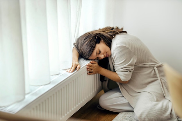 Een zwangere vrouw knuffelt warme radiator