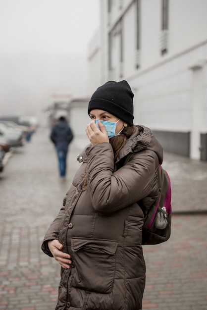 Een zwangere vrouw staat op straat in een Europese stad tijdens een epidemie van coronavirus.