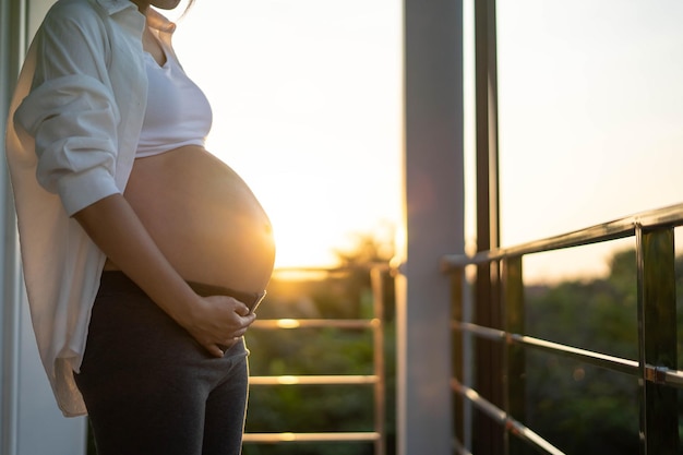 Een zwangere vrouw van 8 maanden raakt zachtjes haar buik aan bij zonsondergang moeder met baby in abbomen zo gelukkige tijd terwijl ze zwanger is