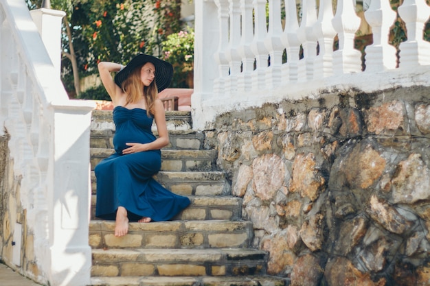 Een zwangere vrouw zit op de stenen trappen van een historisch gebouw. Toerist op excursie. Meisje op vakantie