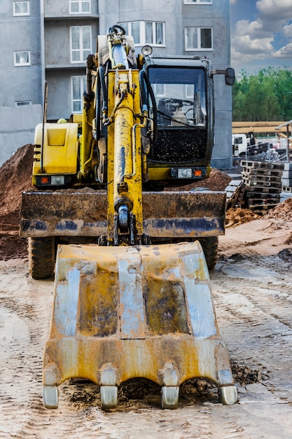 Een zware rupsgraafmachine met een grote bak maakt zich klaar voor het werk. Zware bouwmachines voor grondwerken. Steengroeve graafmachine. Verbetering van het grondgebied.