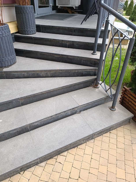 Een zwart met grijze betonnen trap met een leuning en een plantenbak.