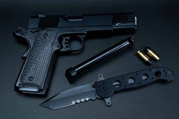 Een zwart pistool, een mes en een zwart pistool liggen op een tafel.